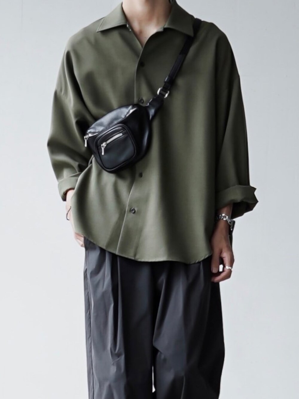 グレー系のチノパンツ、ブラック系のボディバッグ/ウエストポーチ、グリーン系のスニーカーを着用したメンズの夏コーディネートの3枚目の写真