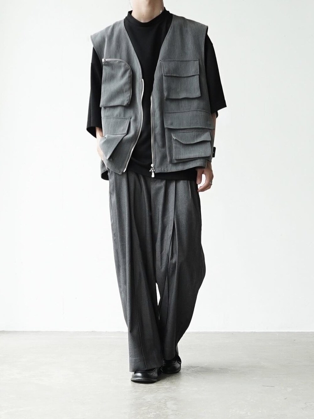 グレー系のベスト、ブラック系のTシャツ/カットソー、グレー系のスラックスを着用したメンズの夏コーディネートの5枚目の写真