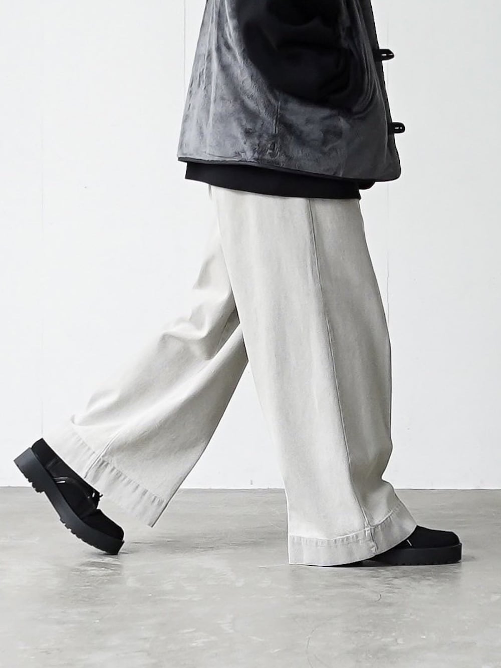 グレー系のベスト、ブラック系のパーカー、グレー系のデニムパンツを着用したメンズの秋コーディネートの4枚目の写真