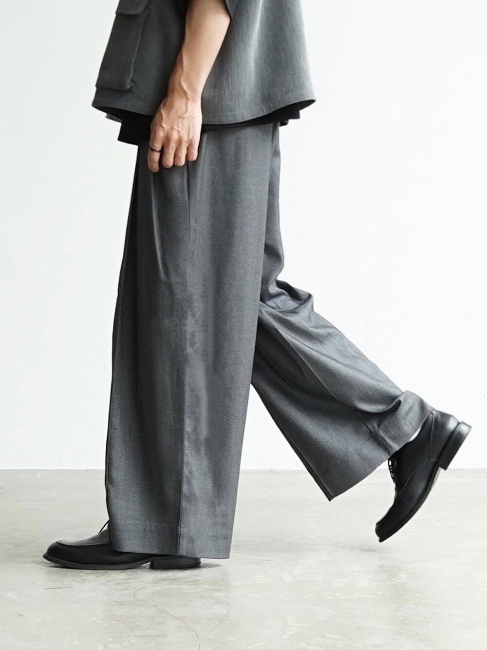 グレー系のベスト、ブラック系のTシャツ/カットソー、グレー系のスラックスを着用したメンズの夏コーディネートの4枚目の写真