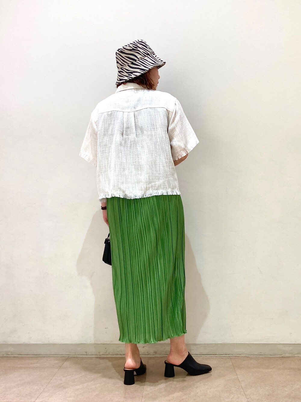 ブラック系のショルダーバッグ、グリーン系のスカート、ホワイト系のシャツ/ブラウスを着用したレディースの春コーディネートの2枚目の写真