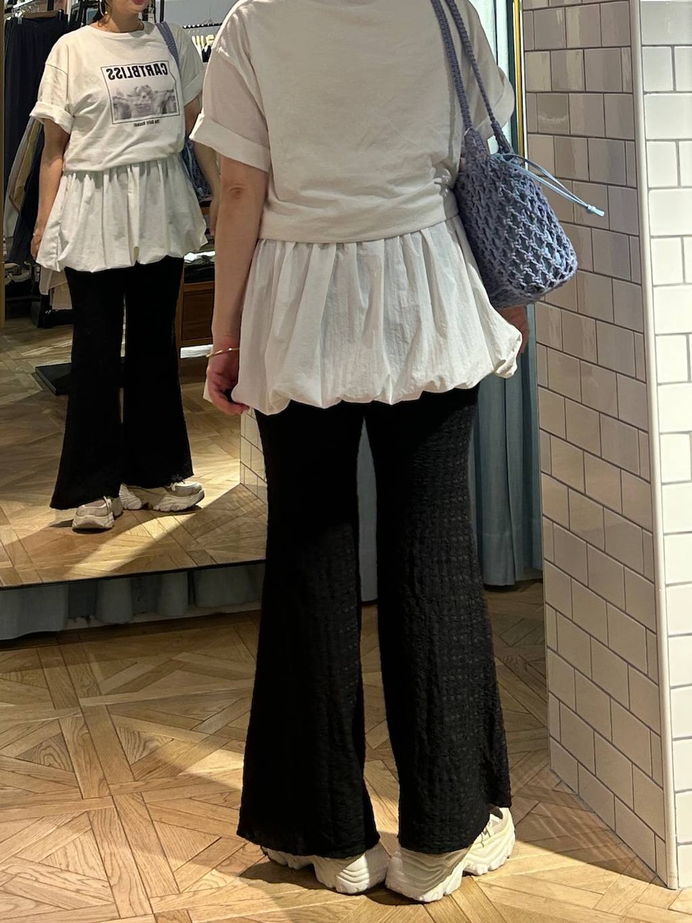 ブルー系のトートバッグ、ホワイト系のTシャツ/カットソー、ベージュ系のスニーカーを着用したレディースの春コーディネートの2枚目の写真