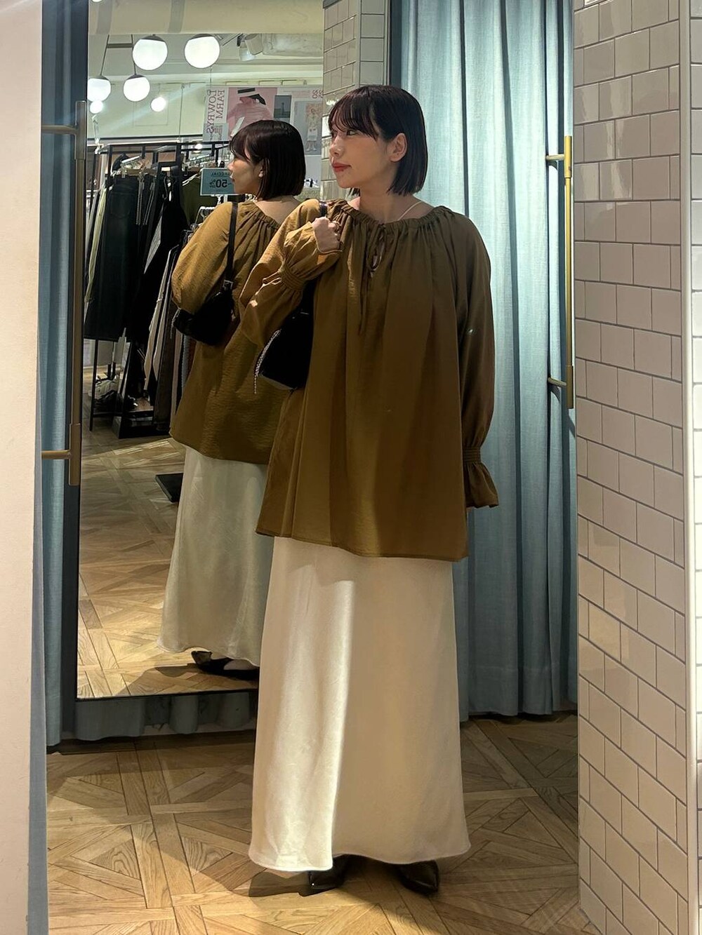 ブラック系のトートバッグ、ブラック系のパンプス、ベージュ系のシャツ/ブラウスを着用したレディースの春コーディネートの4枚目の写真