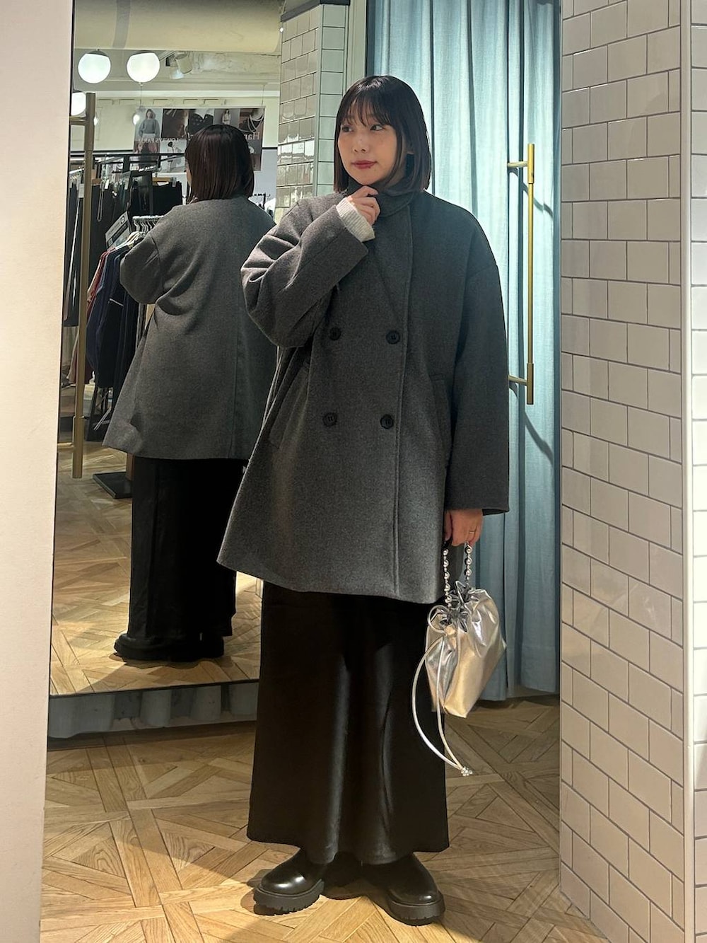 グレー系のニット/セーター、ブラック系のスカート、シルバー系のショルダーバッグを着用したレディースの冬コーディネートの5枚目の写真