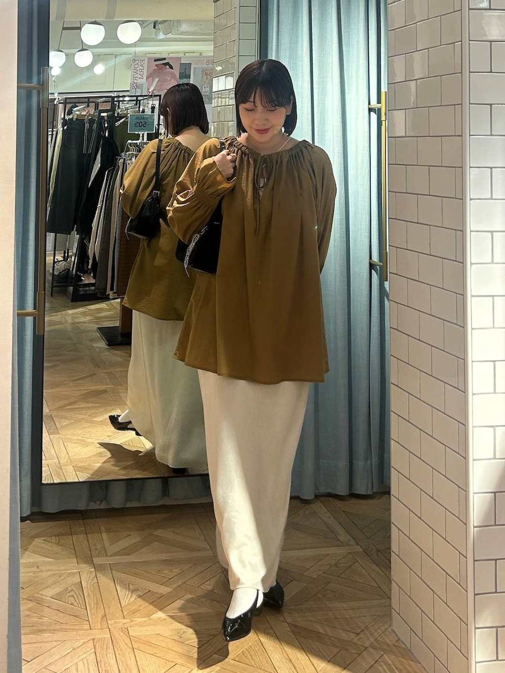 ブラック系のトートバッグ、ブラック系のパンプス、ベージュ系のシャツ/ブラウスを着用したレディースの春コーディネートの2枚目の写真