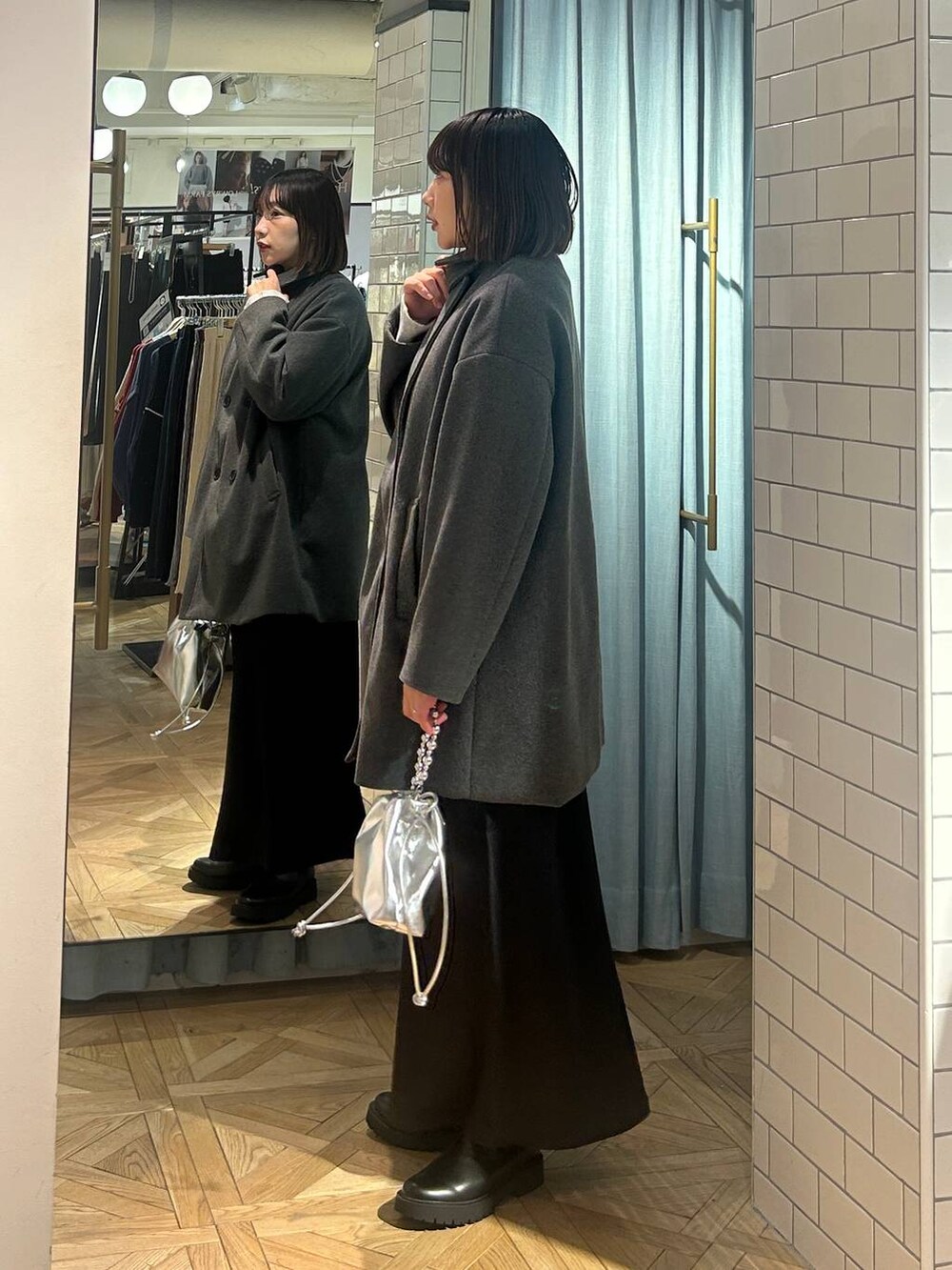 グレー系のニット/セーター、ブラック系のスカート、シルバー系のショルダーバッグを着用したレディースの冬コーディネートの3枚目の写真