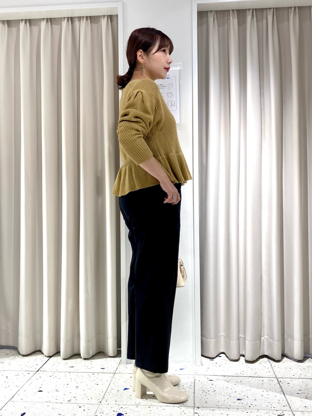 イエロー系のニット/セーター、ブラック系のその他パンツ、ホワイト系のバッグを着用したレディースの秋コーディネートの2枚目の写真