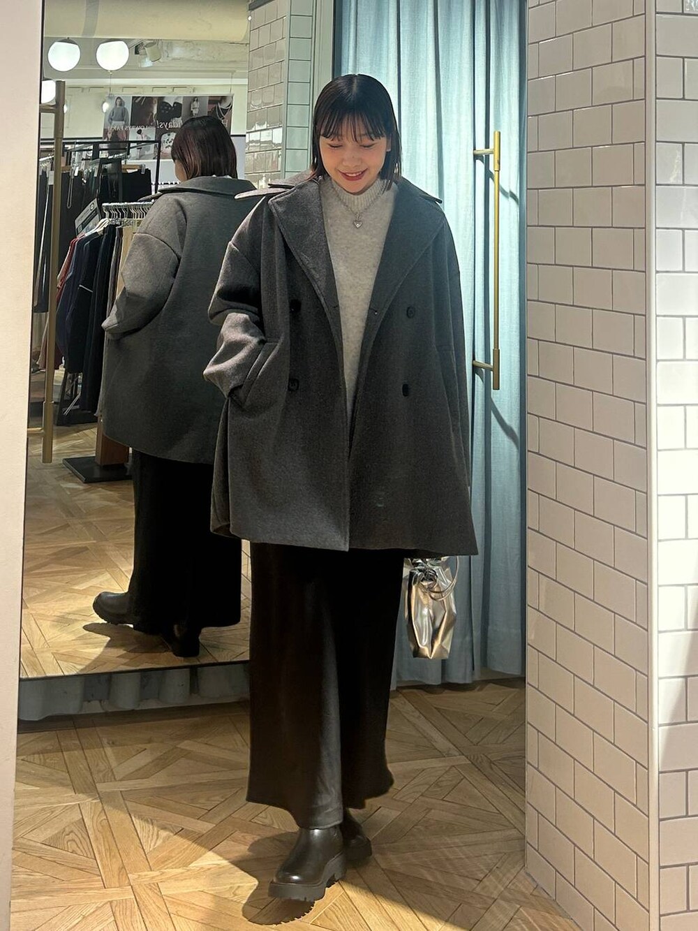 グレー系のニット/セーター、ブラック系のスカート、シルバー系のショルダーバッグを着用したレディースの冬コーディネートの2枚目の写真