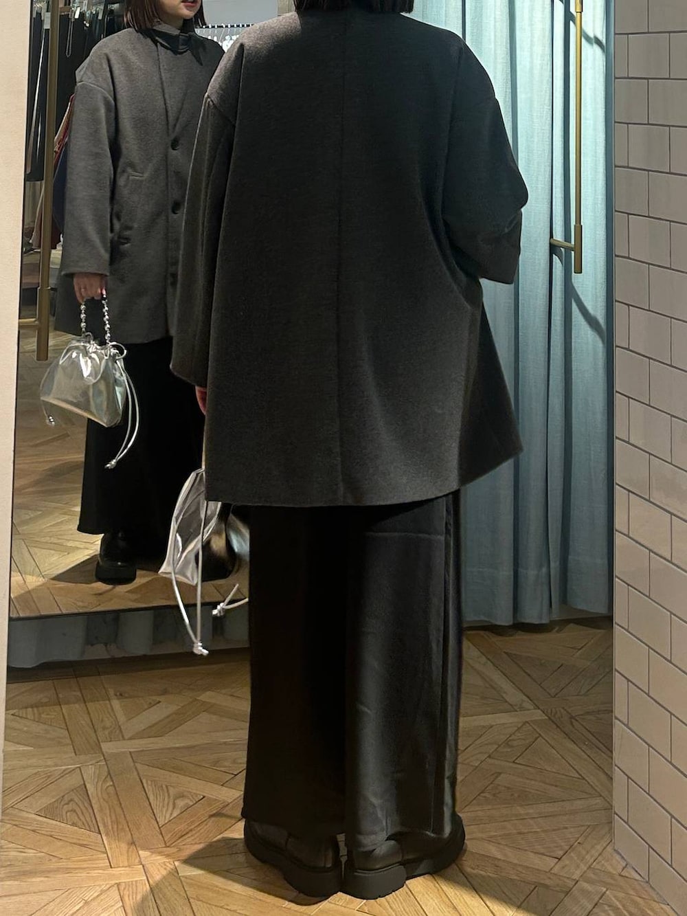 グレー系のニット/セーター、ブラック系のスカート、シルバー系のショルダーバッグを着用したレディースの冬コーディネートの4枚目の写真