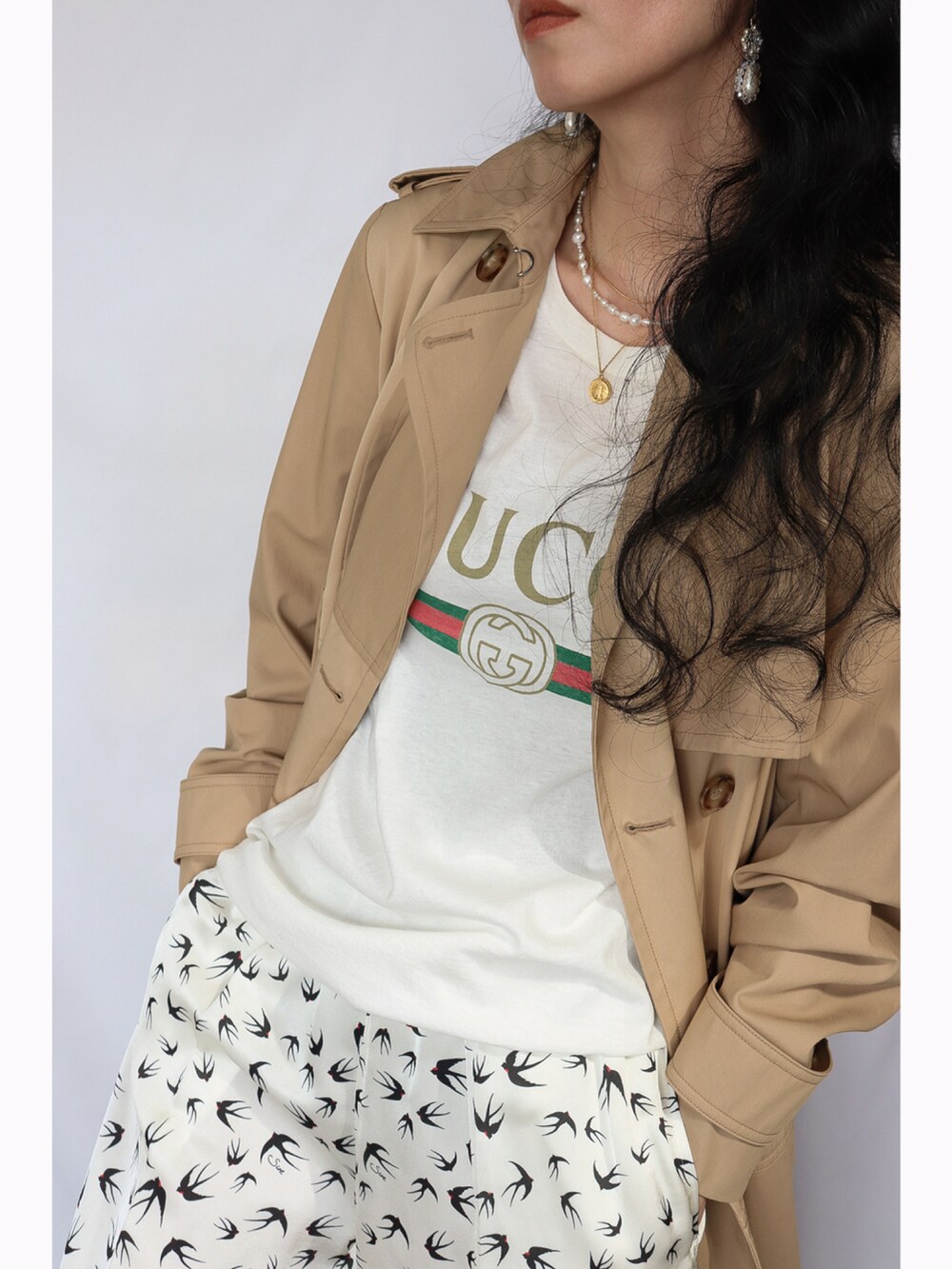 ブラック系のショルダーバッグ、ホワイト系のその他パンツ、ベージュ系のトレンチコートを着用したレディースの春コーディネートの2枚目の写真