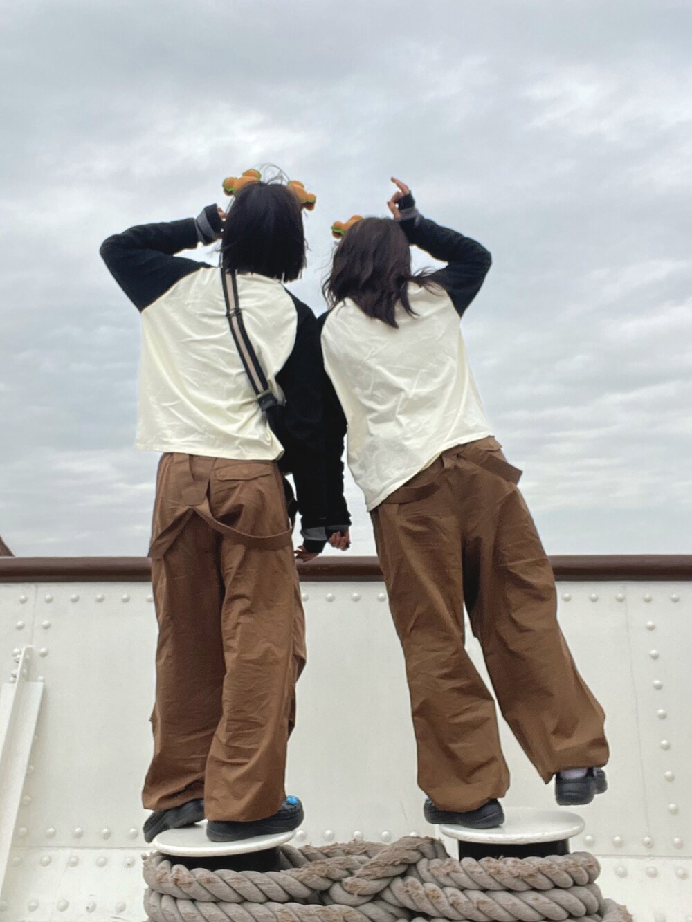 ブラウン系のサロペット/オーバーオール、ホワイト系のTシャツ/カットソー、ブラック系のサンダルを着用したレディースの秋コーディネートの2枚目の写真