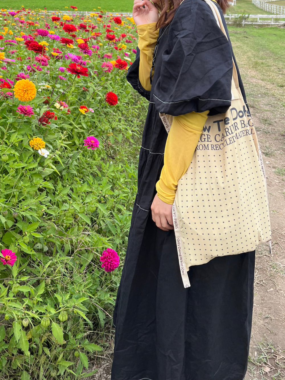 イエロー系のTシャツ/カットソー、ブラック系のワンピース、ベージュ系のバッグを着用したレディースの秋コーディネートの2枚目の写真