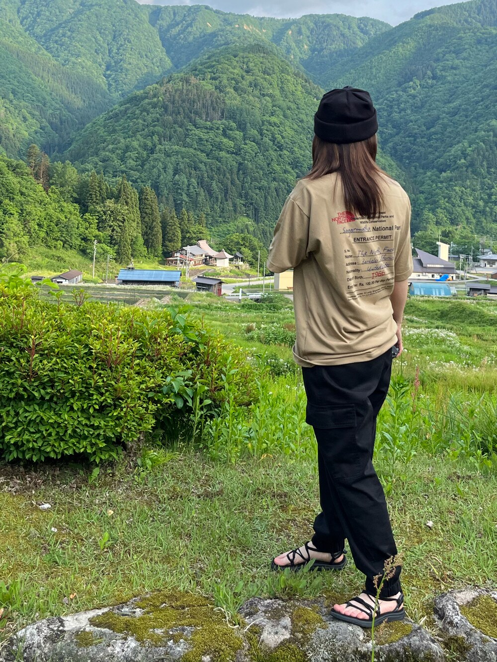 ベージュ系のTシャツ/カットソー、ブラック系のカーゴパンツ、ブラック系のサンダルを着用したレディースの秋コーディネートの2枚目の写真