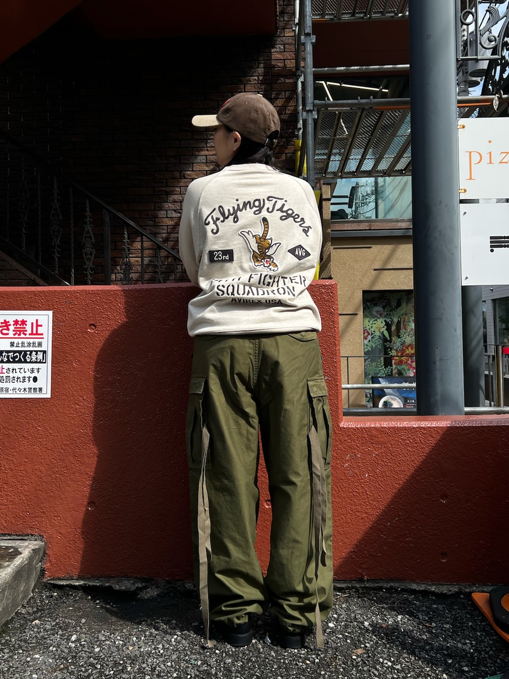 グリーン系のカーゴパンツ、グレー系のスウェット、ブラウン系のキャップを着用したレディースの秋コーディネートの2枚目の写真