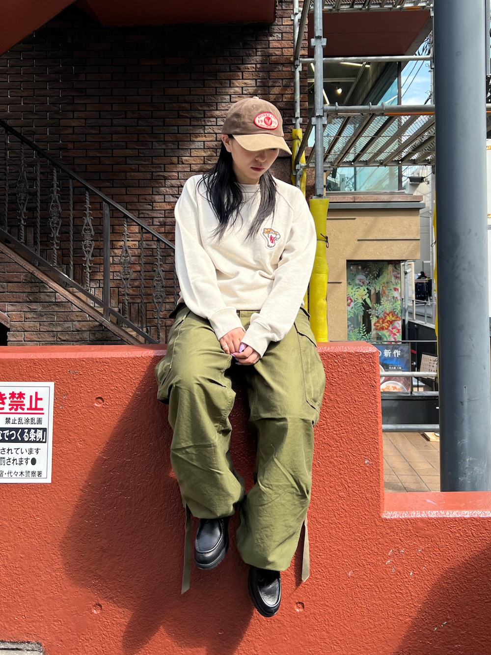 グリーン系のカーゴパンツ、グレー系のスウェット、ブラウン系のキャップを着用したレディースの秋コーディネートの3枚目の写真