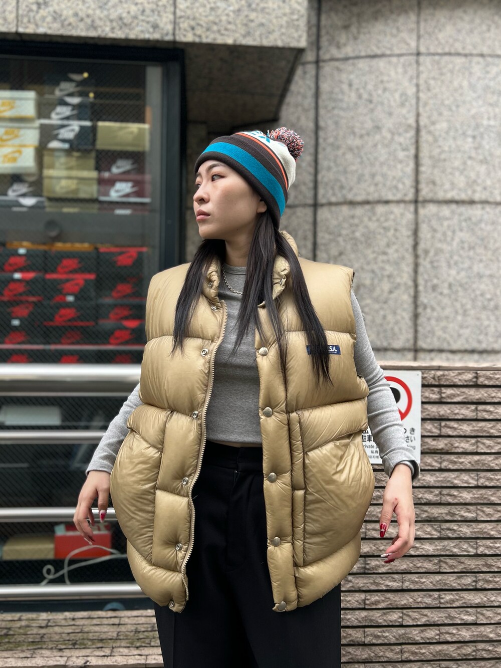 ベージュ系のダウンベスト、グレー系のニットキャップ/ビーニーを着用したレディースの秋コーディネートの2枚目の写真