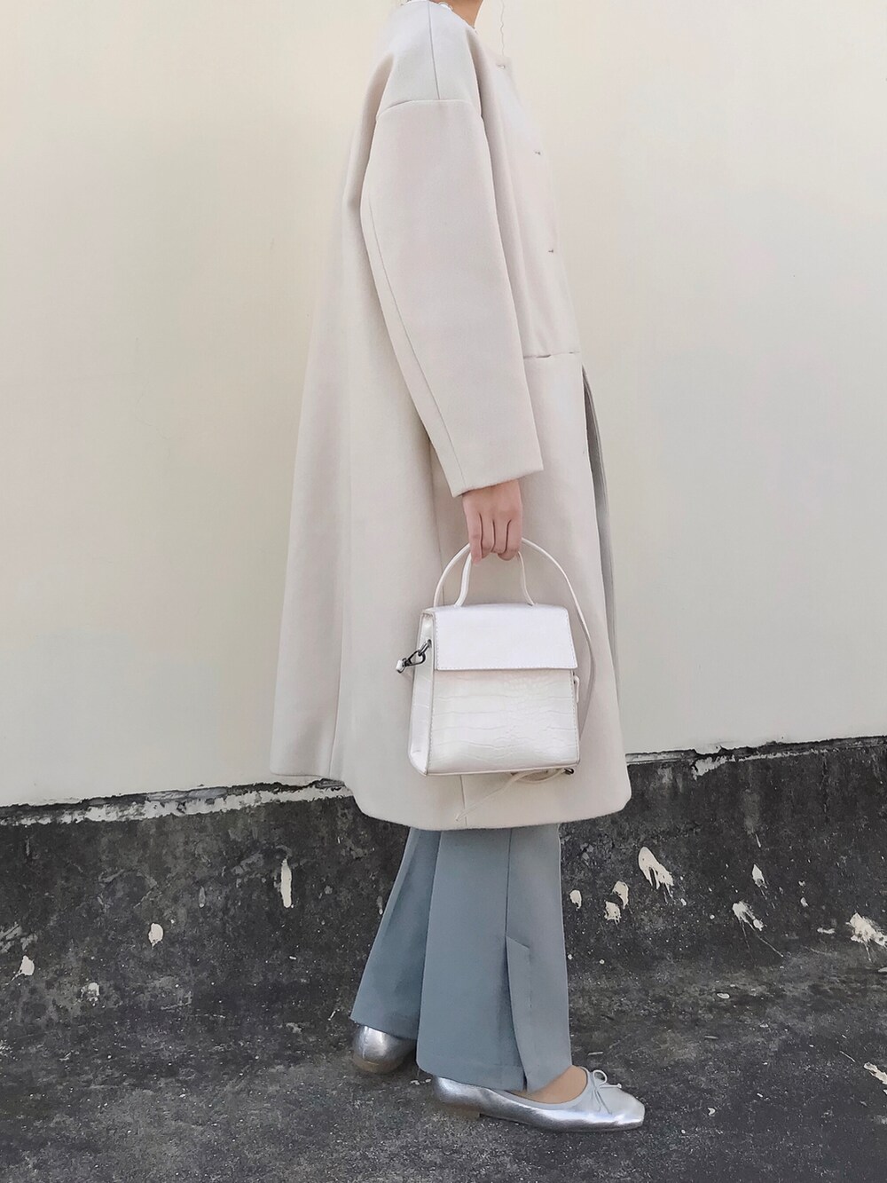ベージュ系のノーカラーコート、ホワイト系のTシャツ/カットソー、ホワイト系のショルダーバッグを着用したレディースの冬コーディネートの2枚目の写真