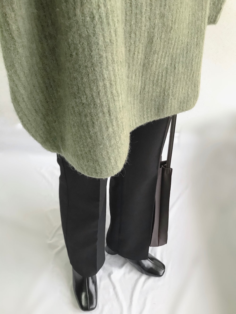 グリーン系のニット/セーター、ブラック系のその他パンツ、ブラウン系のショルダーバッグを着用したレディースの春コーディネートの2枚目の写真