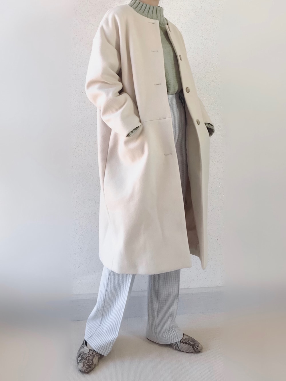 グリーン系のニット/セーター、ベージュ系のノーカラーコート、ホワイト系のスラックスを着用したレディースの春コーディネートの2枚目の写真