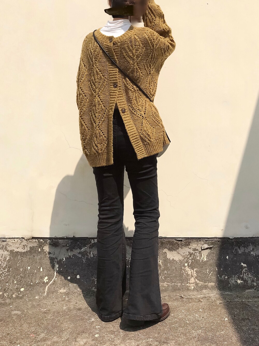 ブラウン系のニット/セーター、ブラック系のデニムパンツ、ブラウン系のローファーを着用したレディースの春コーディネートの2枚目の写真