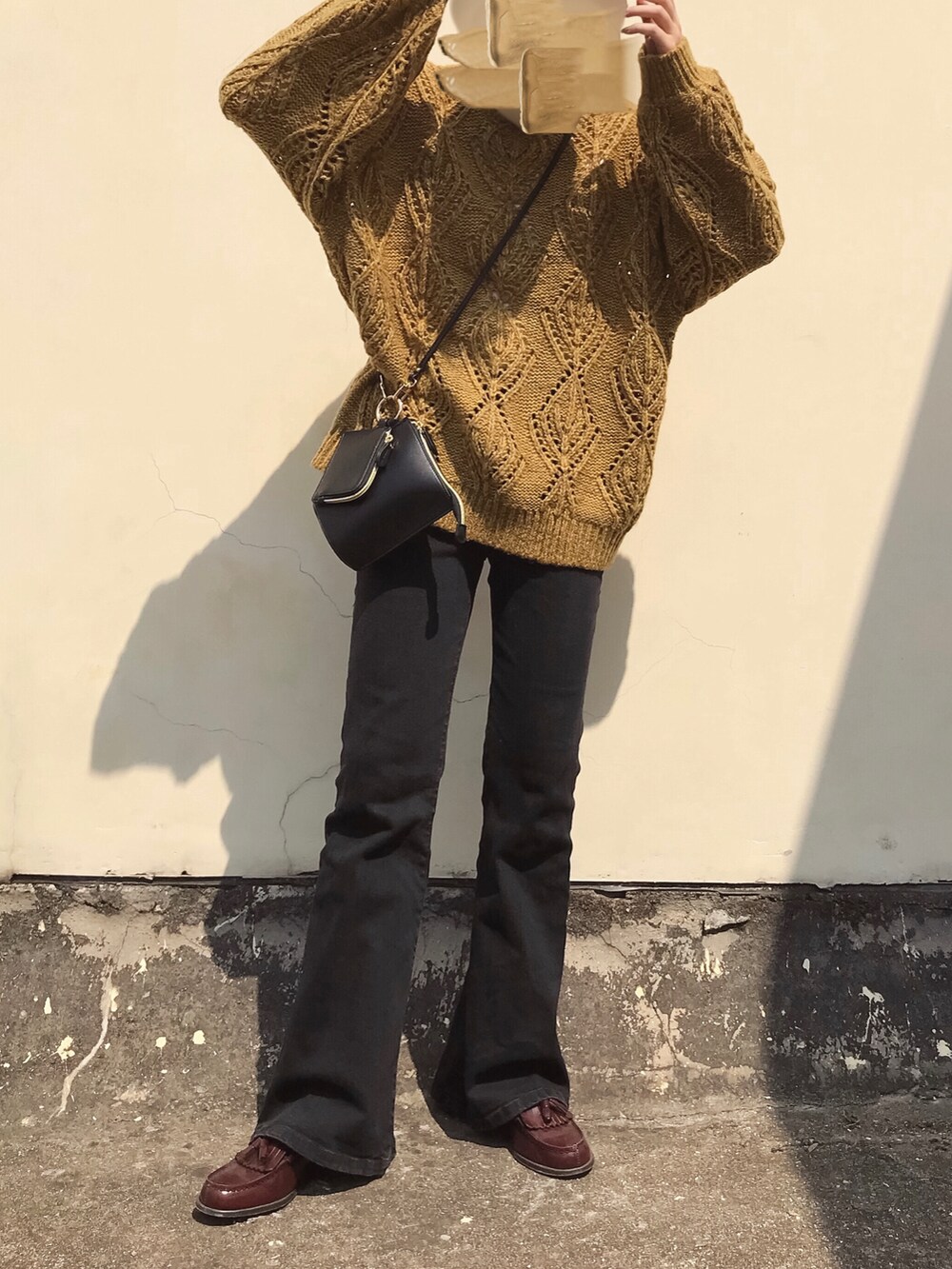 ブラウン系のニット/セーター、ブラック系のデニムパンツ、ブラウン系のローファーを着用したレディースの春コーディネートの5枚目の写真