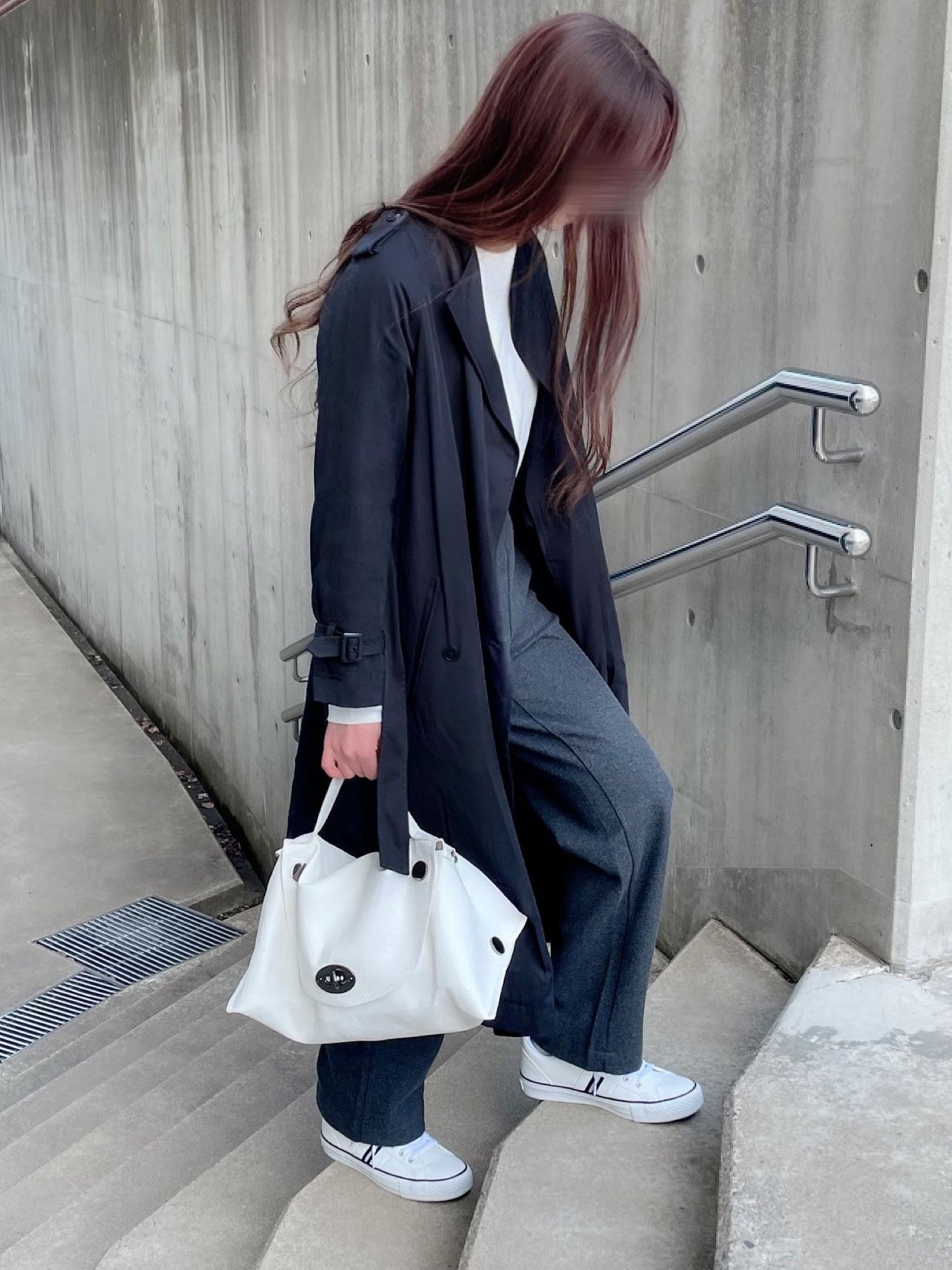 ブラック系のトレンチコート、グレー系のパンツ、ホワイト系のスニーカーを着用したレディースの春コーディネートの2枚目の写真