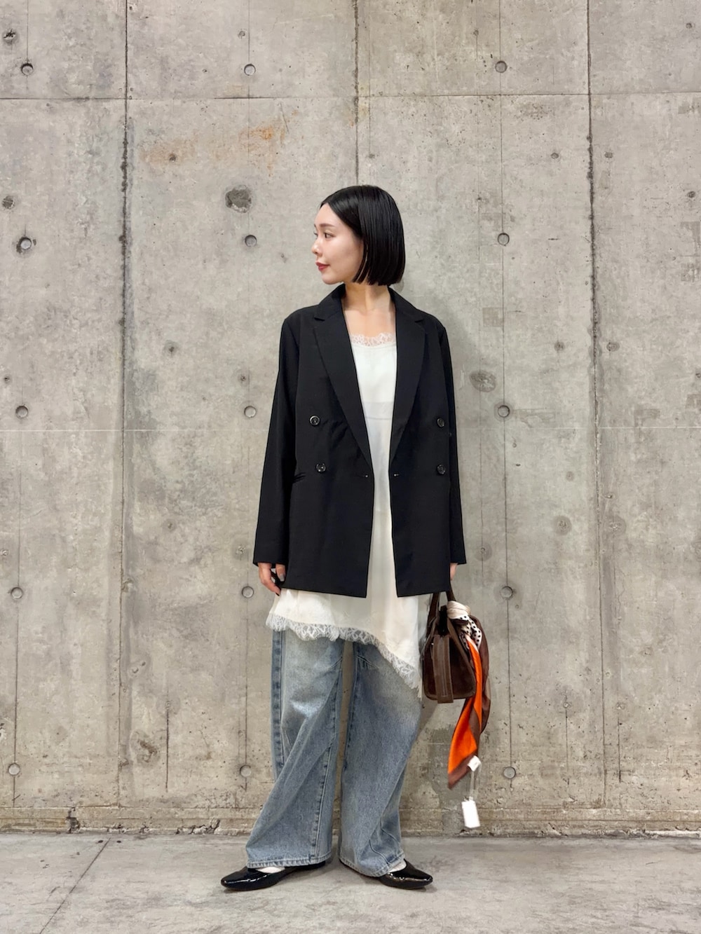 ブラック系のテーラードジャケット、ホワイト系のキャミソール、ブルー系のデニムパンツを着用したレディースの春コーディネートの4枚目の写真