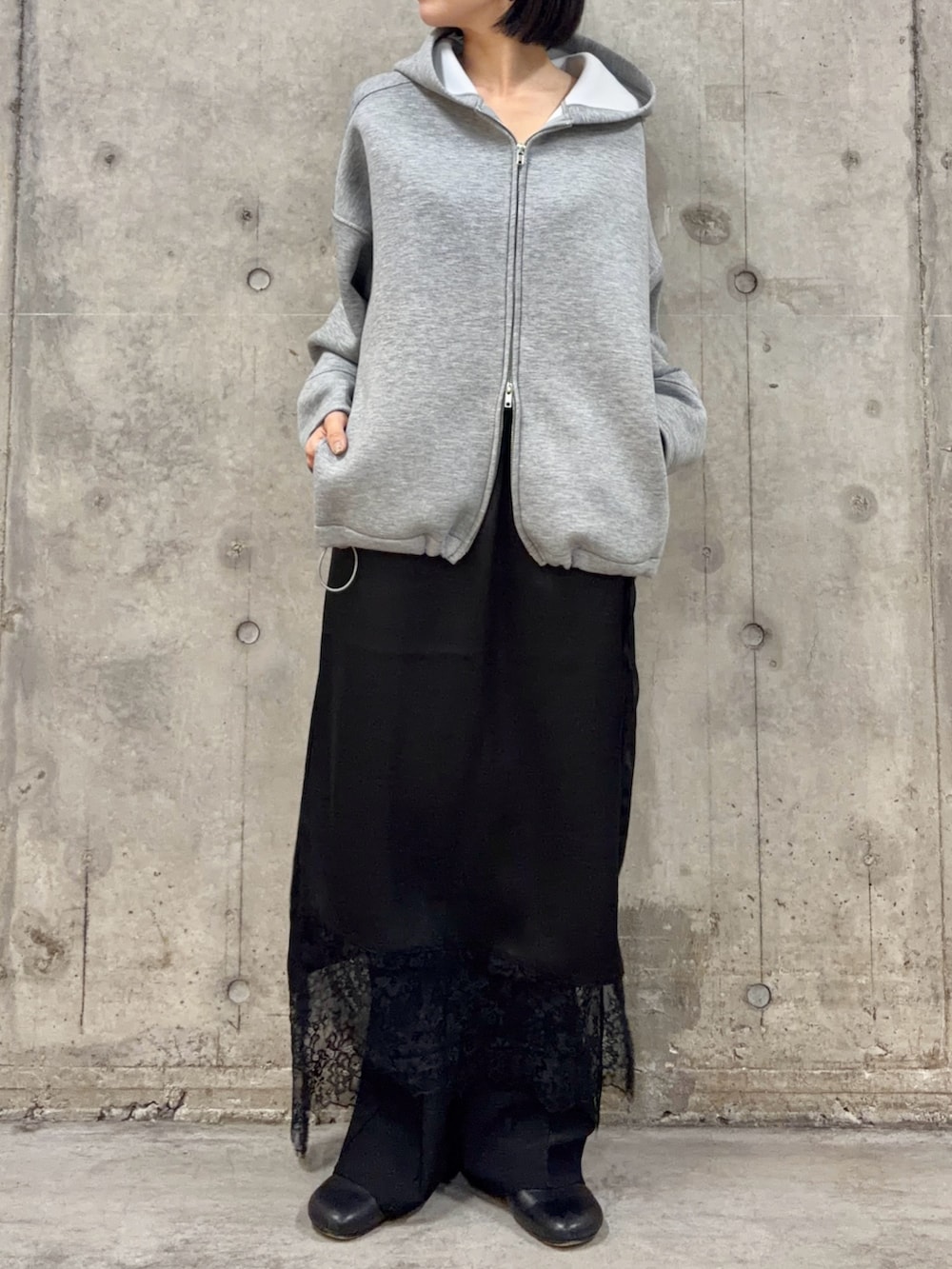 グレー系のパーカー、ブラック系のスカート、ブラック系のその他パンツを着用したレディースの冬コーディネートの3枚目の写真