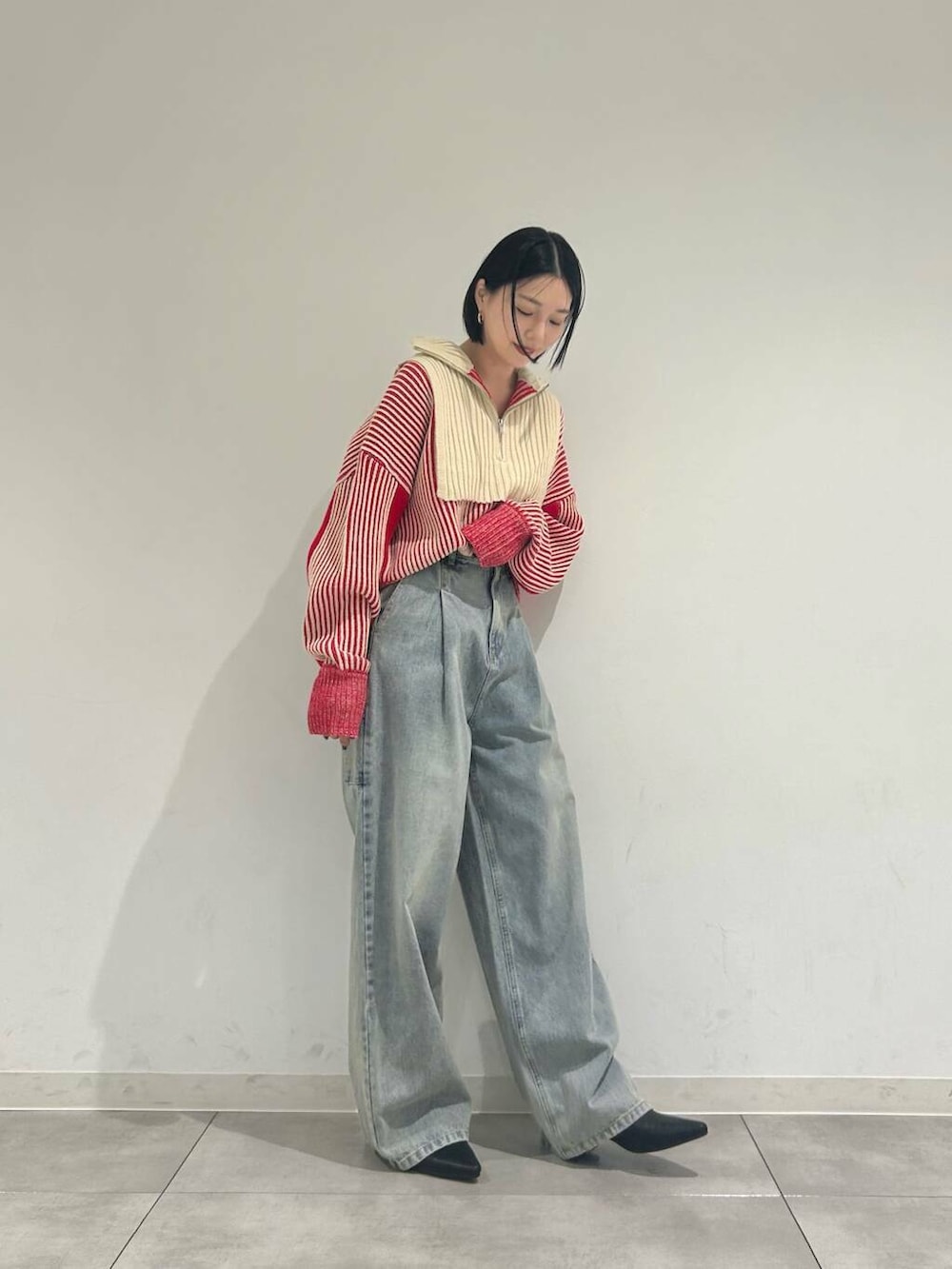 レッド系のニット/セーター、ブルー系のデニムパンツ、ブラック系のブーツを着用したレディースの冬コーディネートの2枚目の写真