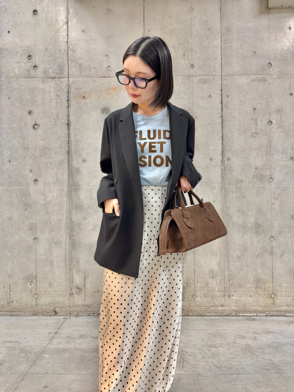 ブラック系のテーラードジャケット、ホワイト系のスカート、ブラック系のパンプスを着用したレディースの春コーディネートの2枚目の写真