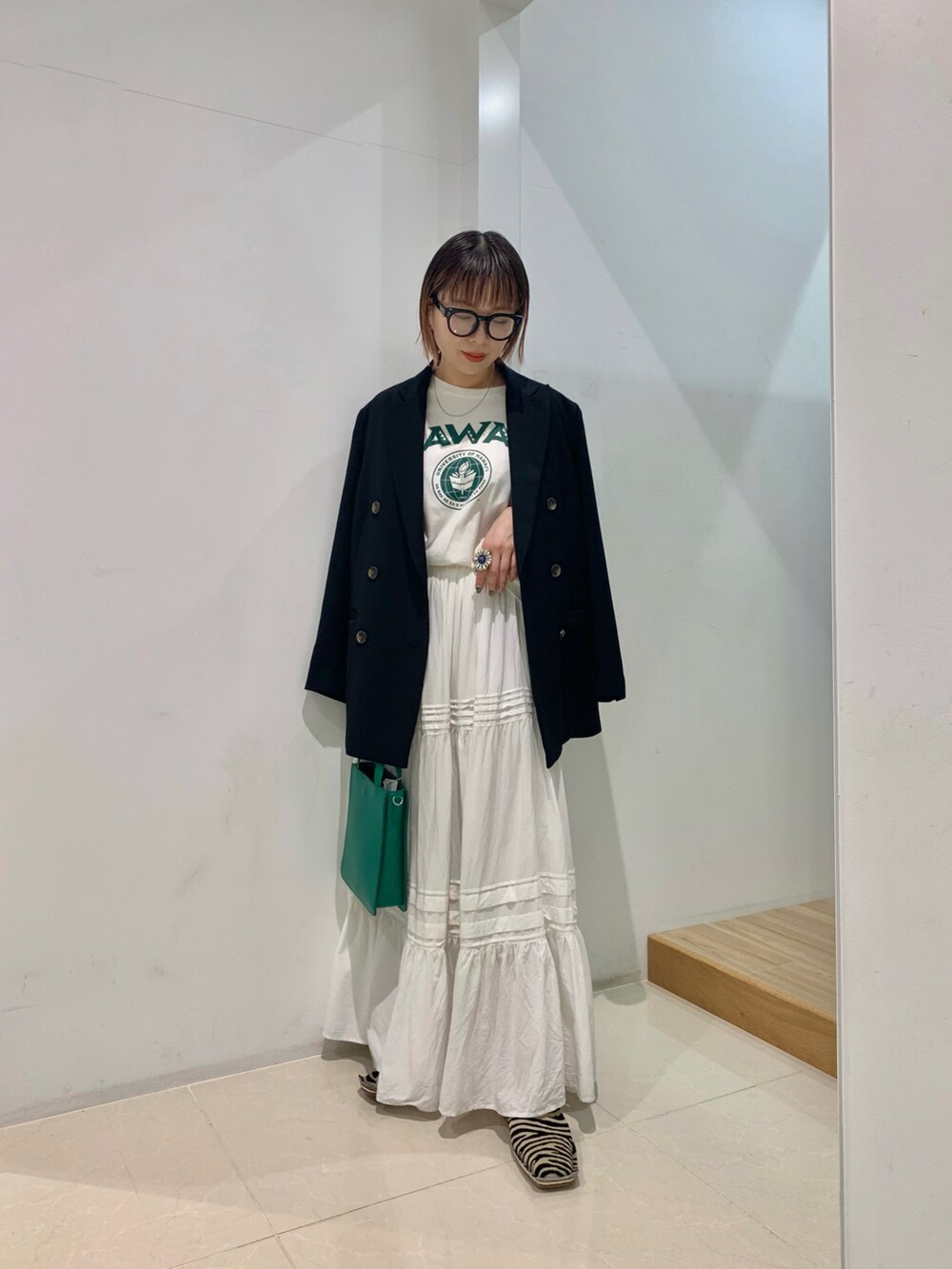 ブラック系のテーラードジャケット、グリーン系のTシャツ/カットソー、グリーン系のトートバッグを着用したレディースの春コーディネートの2枚目の写真