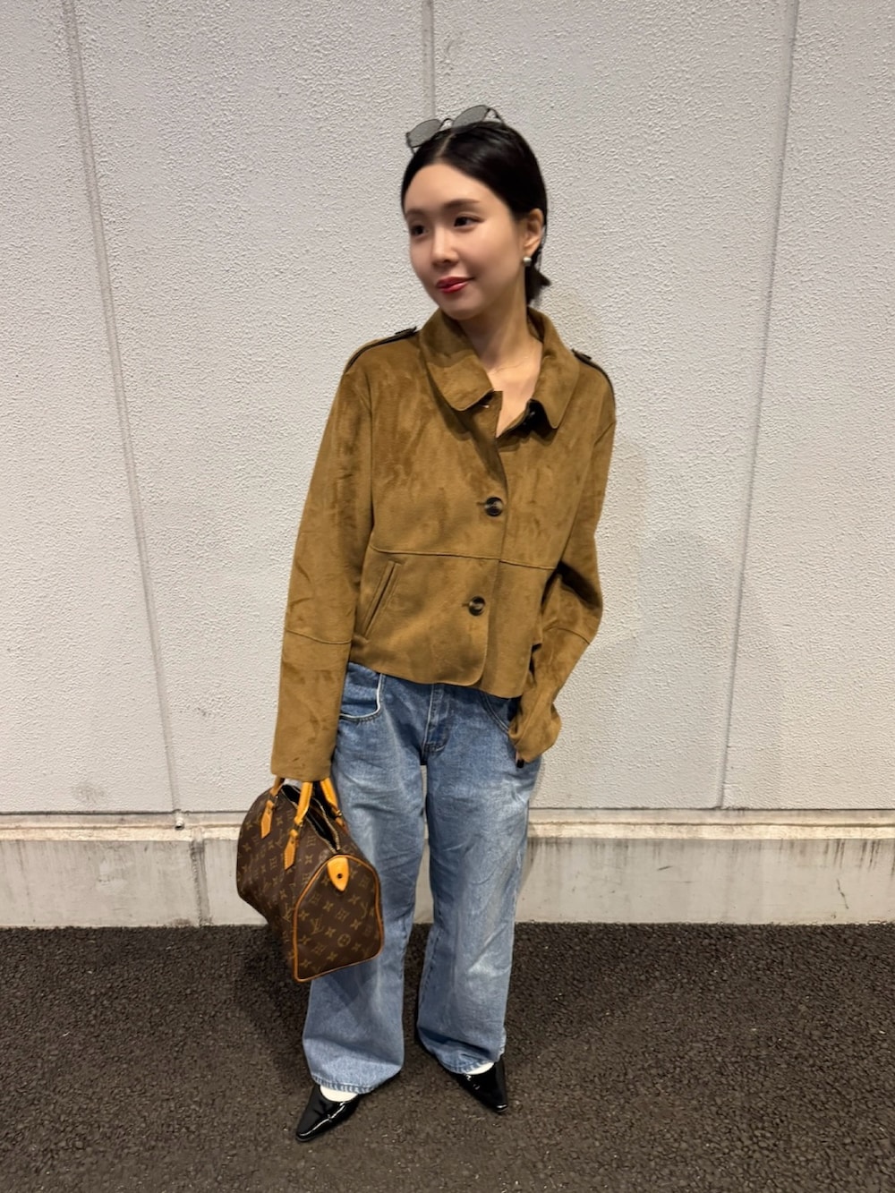 ブルー系のデニムパンツ、ブラック系のパンプス、シルバー系のピアス（両耳用）を着用したレディースの春コーディネートの2枚目の写真