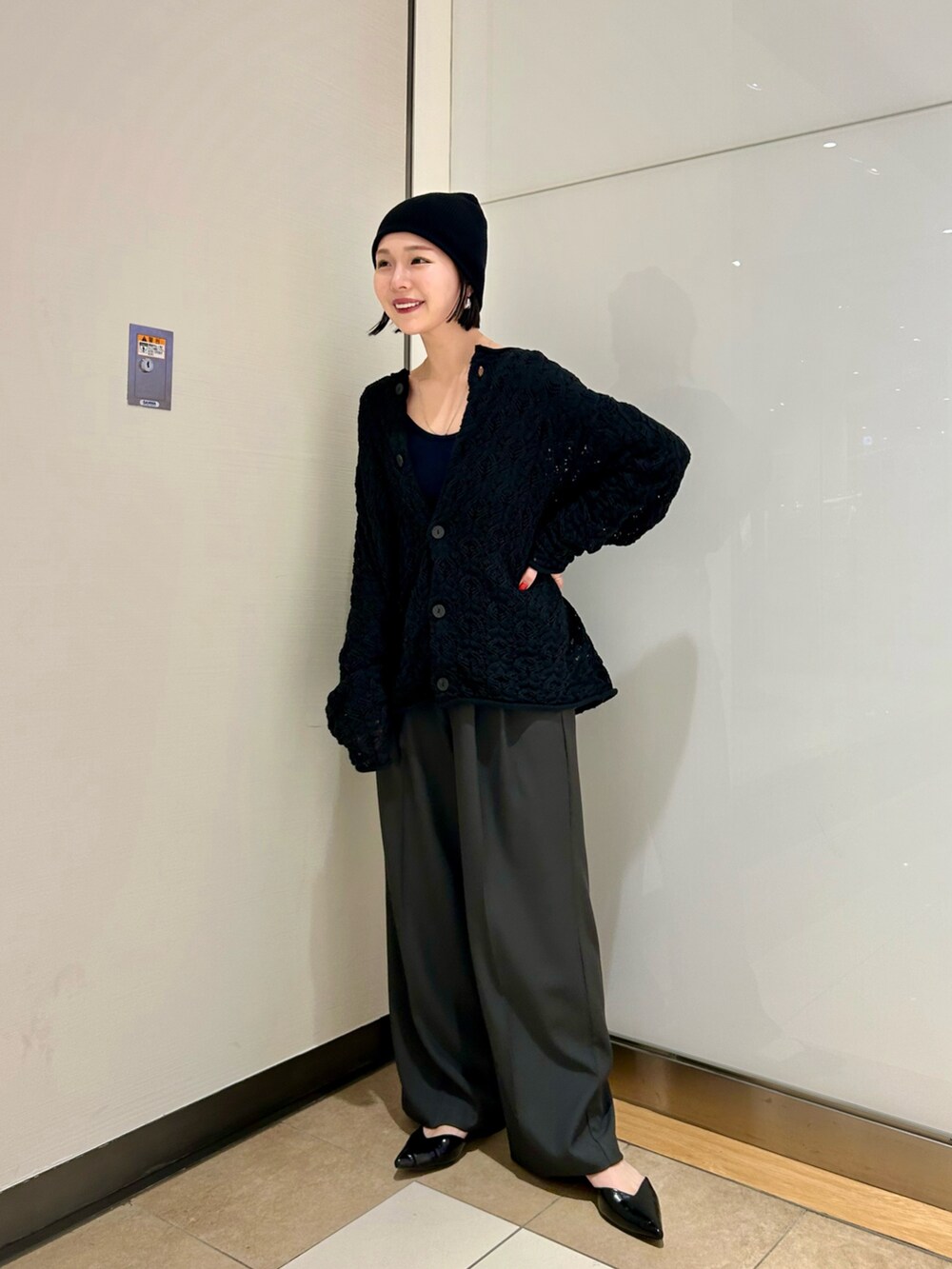 ベージュ系のその他パンツ、ブラック系のカーディガン/ボレロ、シルバー系のピアス（両耳用）を着用したレディースの冬コーディネートの2枚目の写真