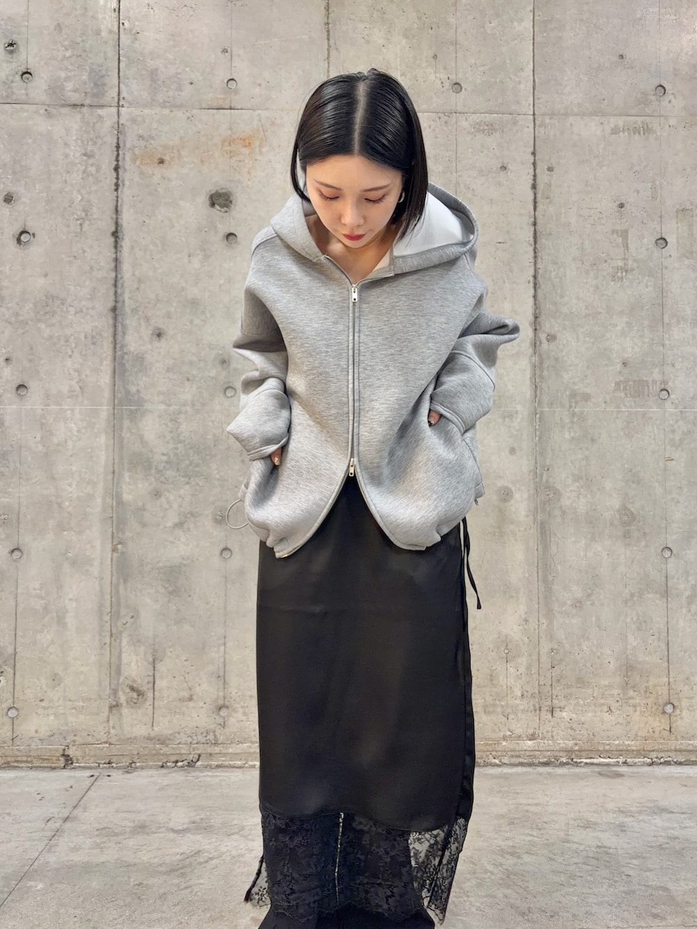 グレー系のパーカー、ブラック系のスカート、ブラック系のその他パンツを着用したレディースの冬コーディネートの2枚目の写真