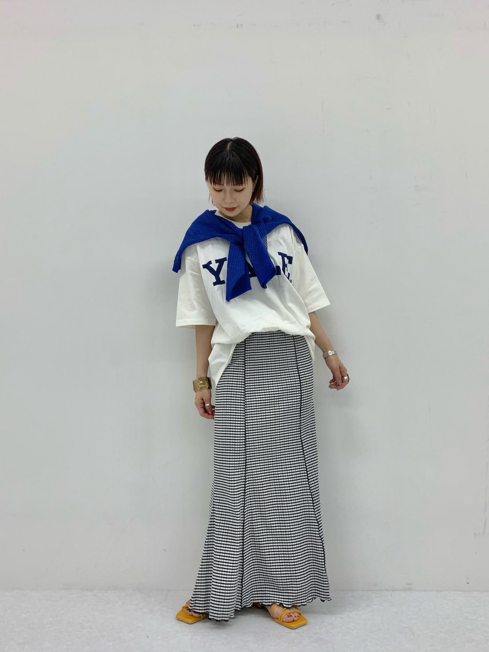 グリーン系のスカート、ホワイト系のTシャツ/カットソー、イエロー系のサンダルを着用したレディースの夏コーディネートの2枚目の写真
