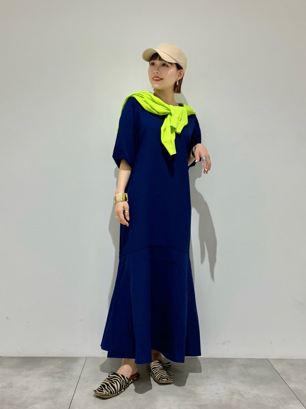 オレンジ系のカーディガン/ボレロ、ブルー系のワンピース、ベージュ系のキャップを着用したレディースの夏コーディネートの2枚目の写真