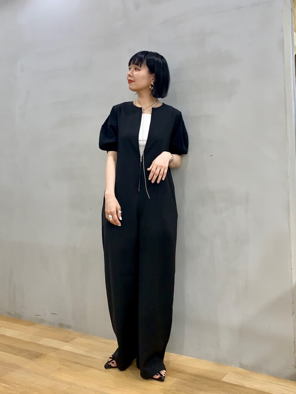 ブラック系のサロペット/オーバーオール、ブラック系のサンダル、ホワイト系のタンクトップを着用したレディースの夏コーディネートの2枚目の写真