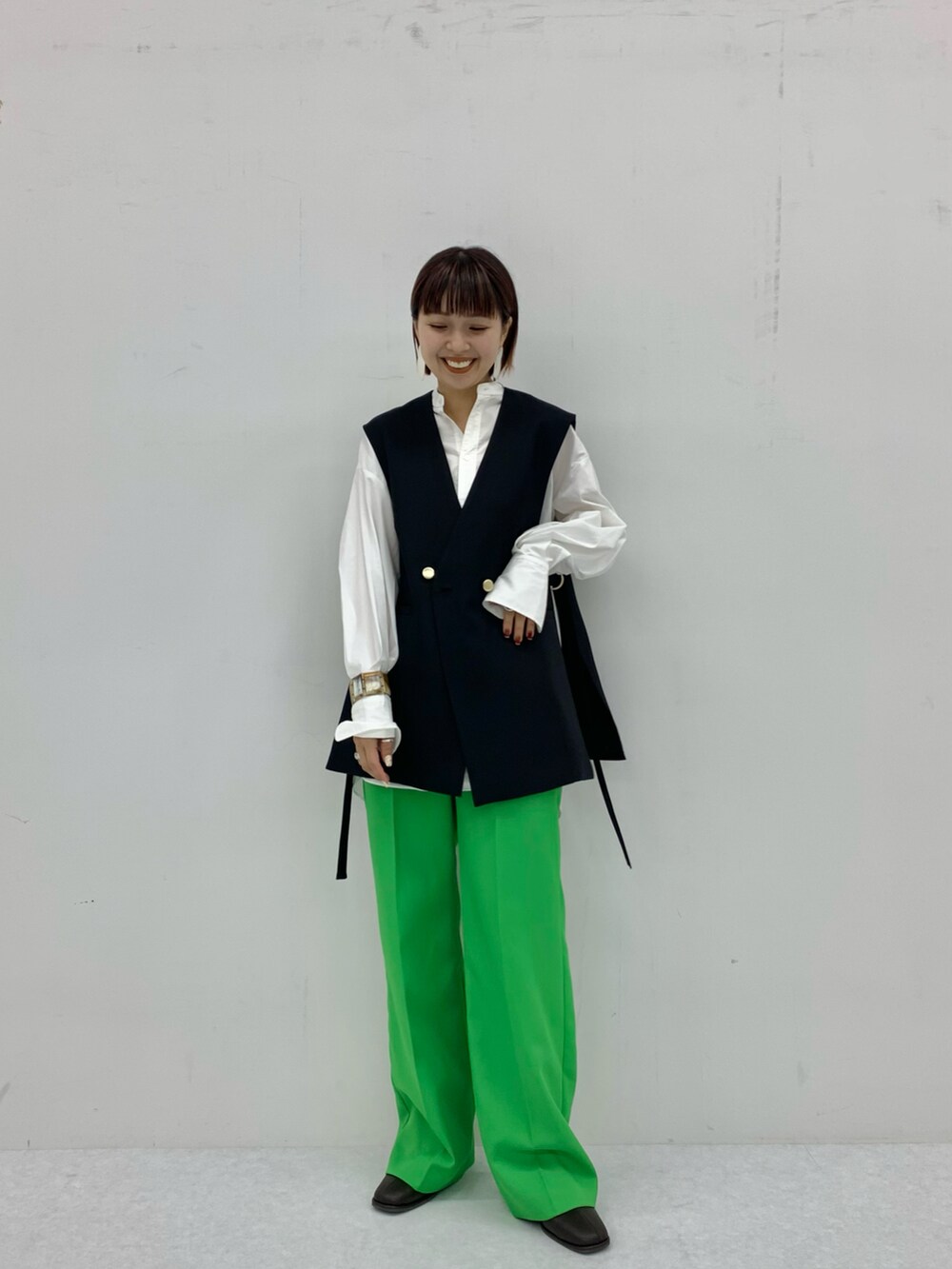 ブラック系のベスト、ブルー系のシャツ/ブラウス、グリーン系のスラックスを着用したレディースの秋コーディネートの2枚目の写真