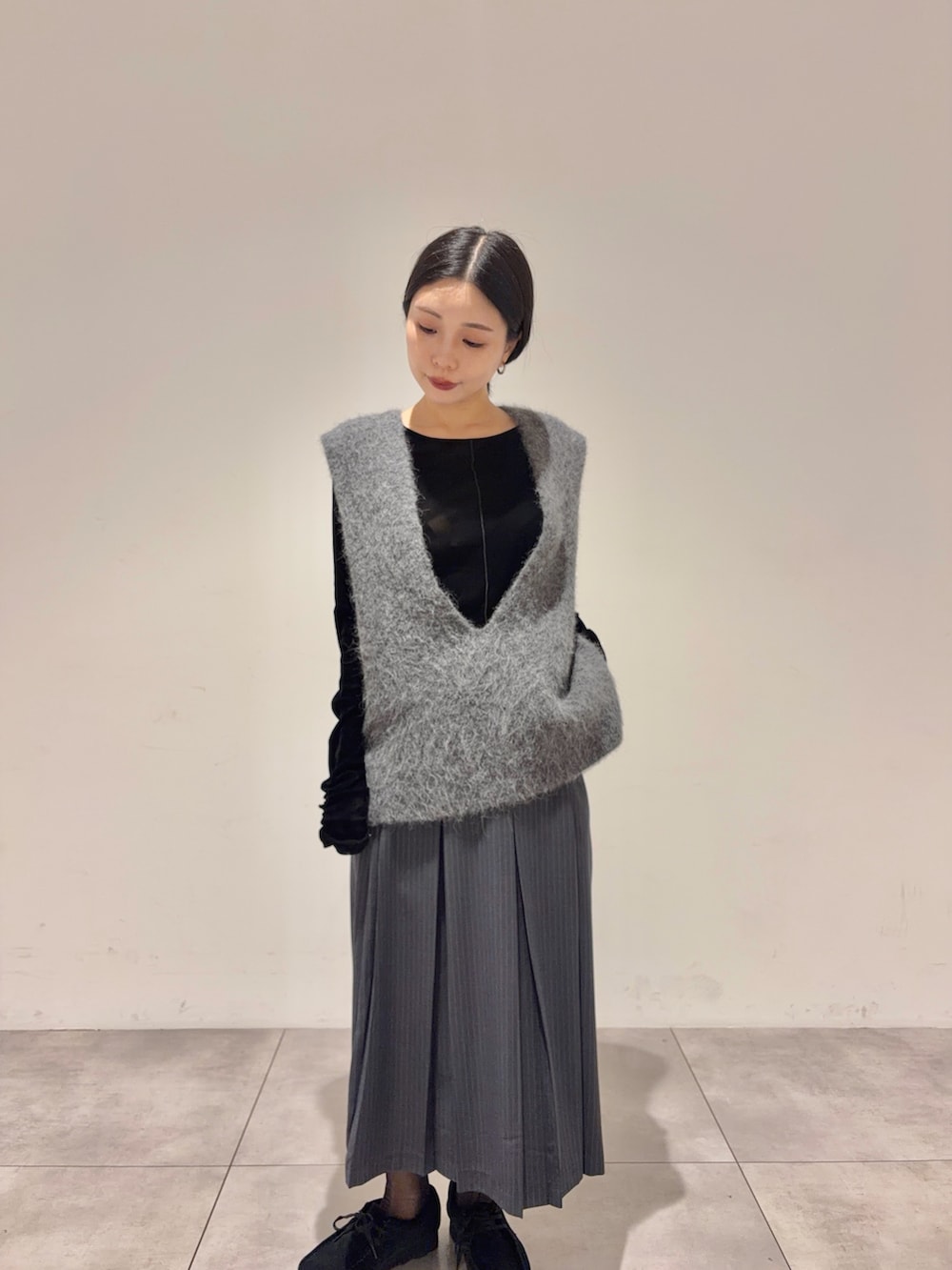 ブラック系のTシャツ/カットソー、グレー系のスカート、ブラック系のブーツを着用したレディースの秋コーディネートの2枚目の写真