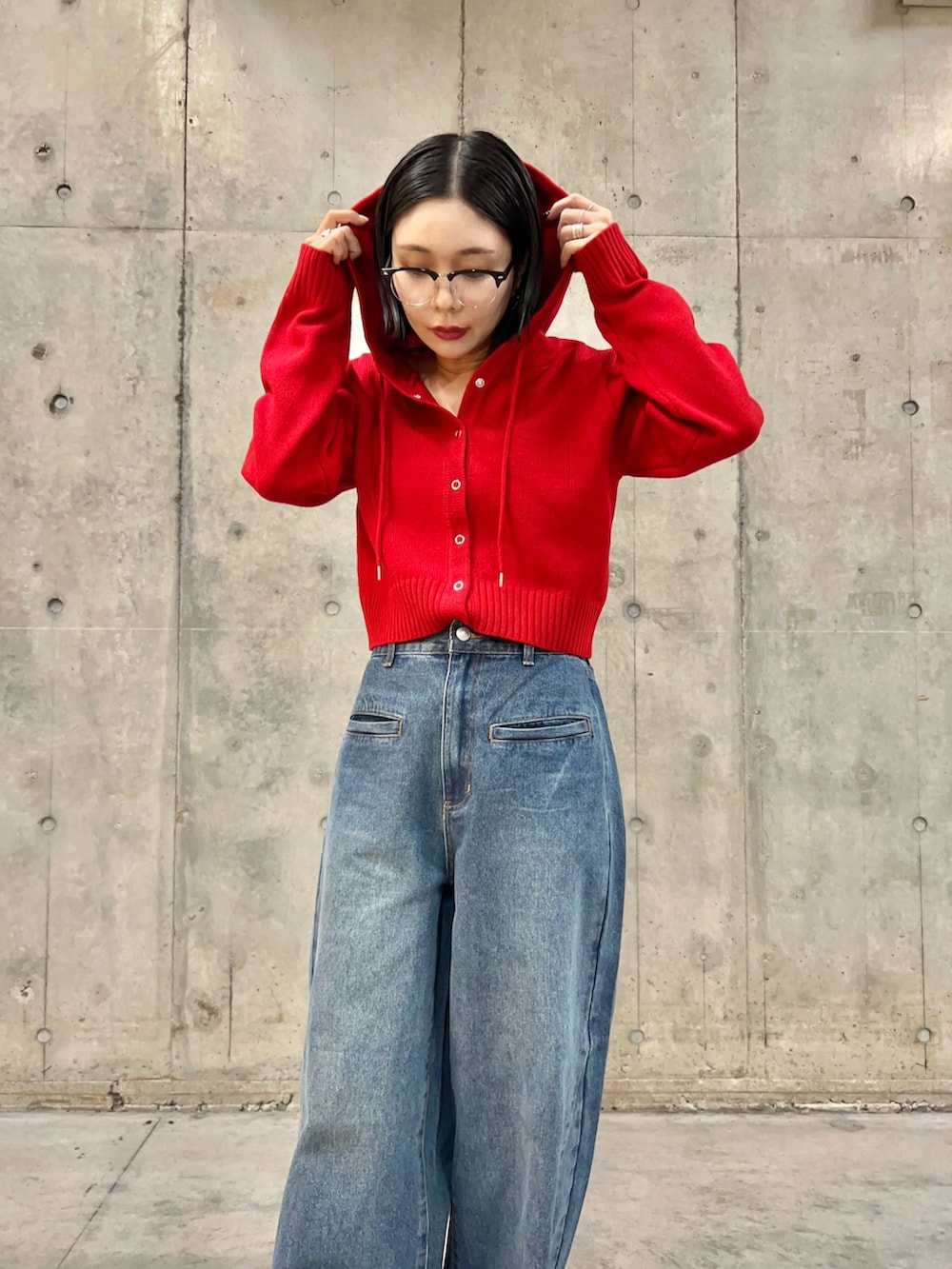 レッド系のニット/セーター、ブルー系のデニムパンツ、ブラック系のメガネを着用したレディースの秋コーディネートの2枚目の写真