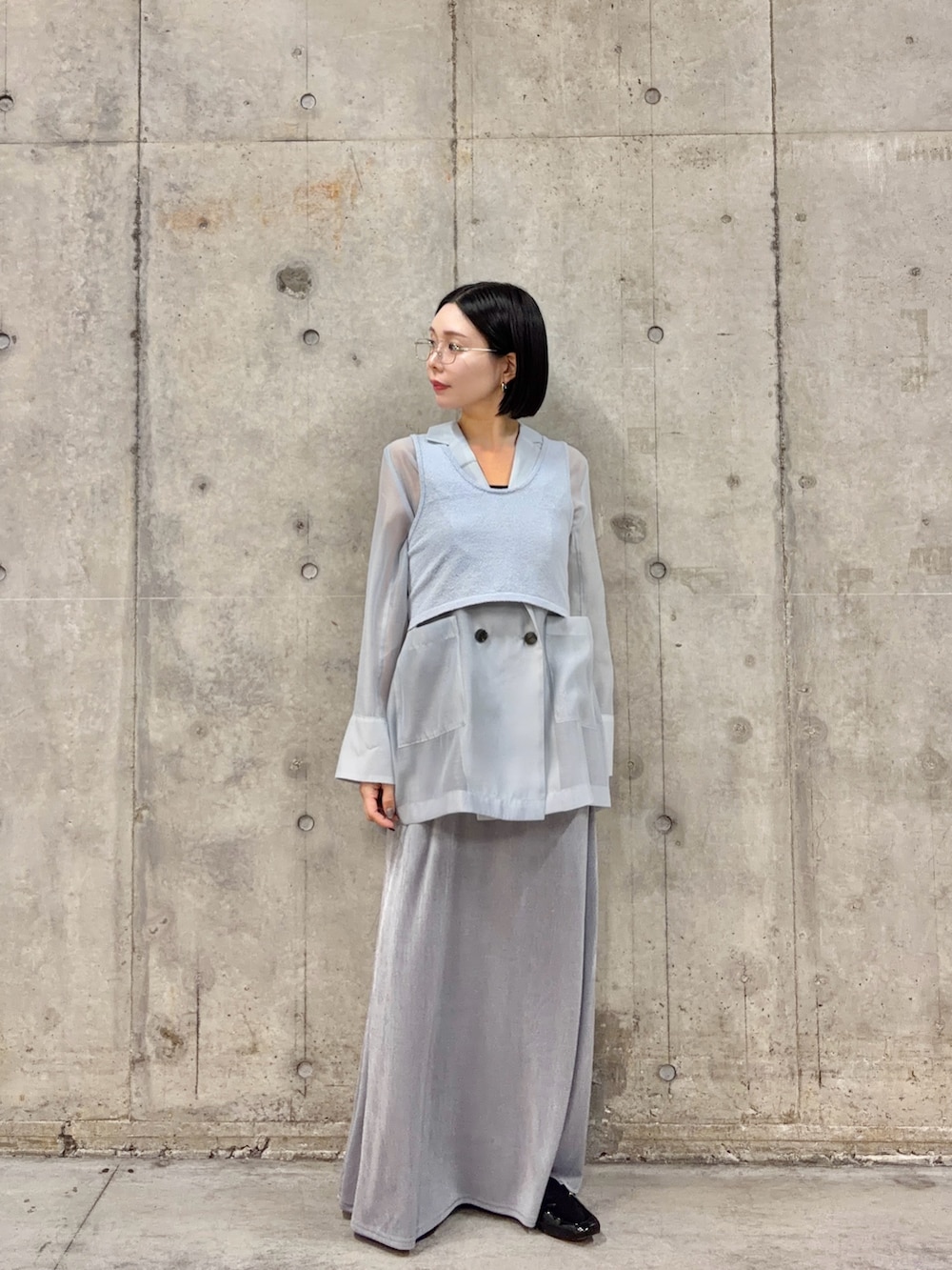 ブルー系のテーラードジャケット、ブルー系のニット/セーター、グレー系のスカートを着用したレディースの春コーディネートの2枚目の写真