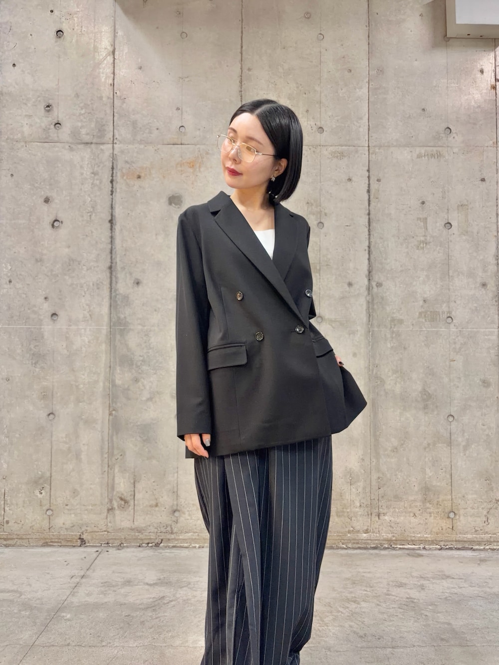 ブラック系のテーラードジャケット、ブルー系のスカート、ブラック系のブーツを着用したレディースの春コーディネートの3枚目の写真