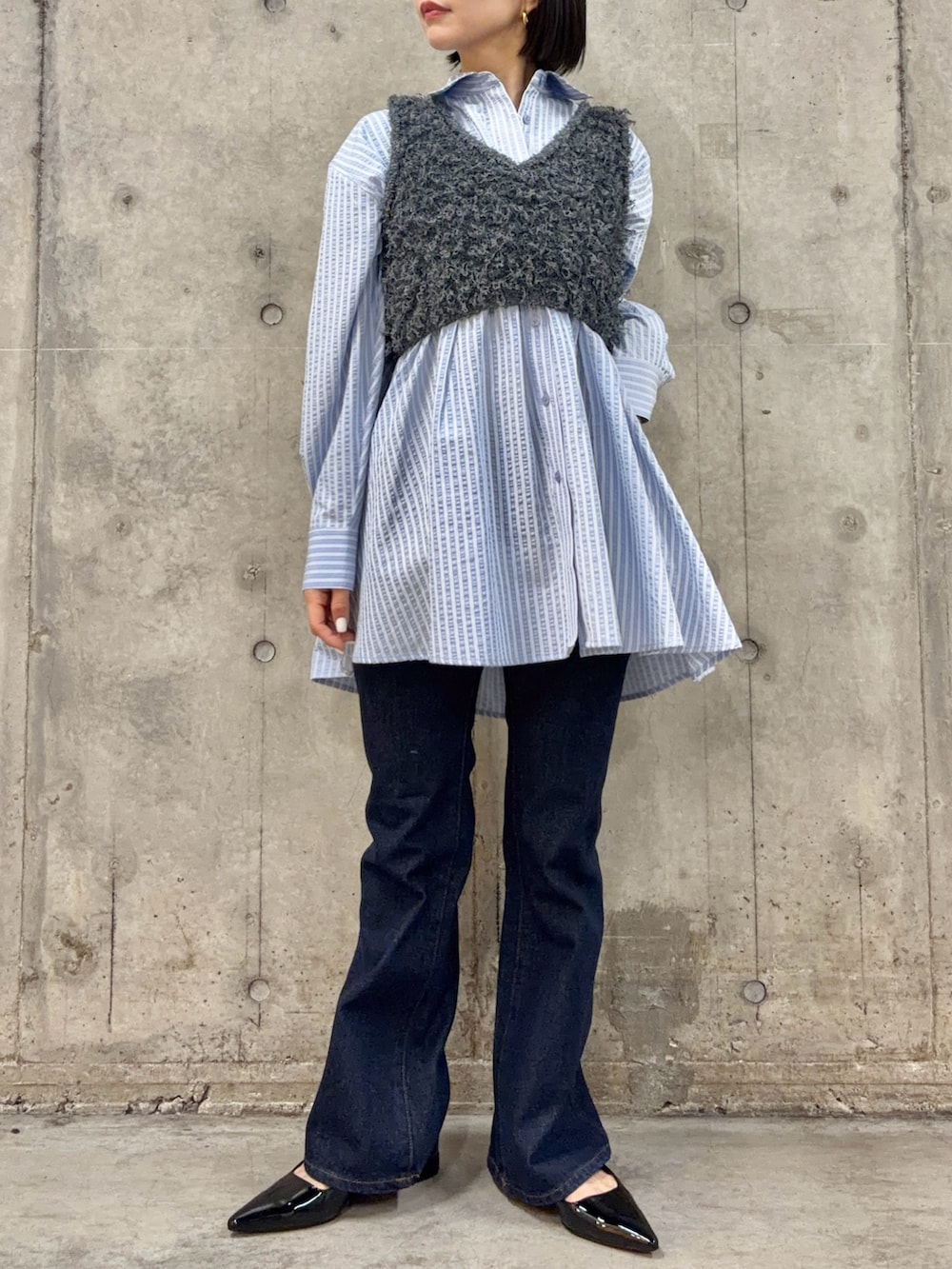 グレー系のベスト、ブルー系のワンピース、ブルー系のデニムパンツを着用したレディースの冬コーディネートの2枚目の写真