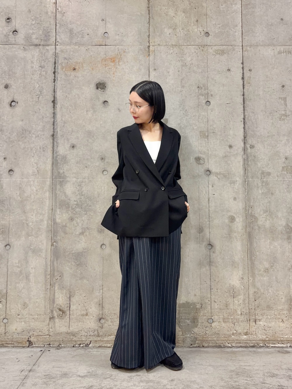 ブラック系のテーラードジャケット、ブルー系のスカート、ブラック系のブーツを着用したレディースの春コーディネートの2枚目の写真