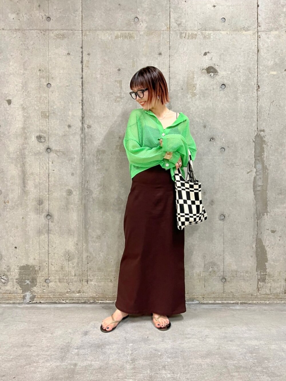 グリーン系のカーディガン/ボレロ、ブラウン系のスカート、ゴールド系のネックレスを着用したレディースの夏コーディネートの2枚目の写真