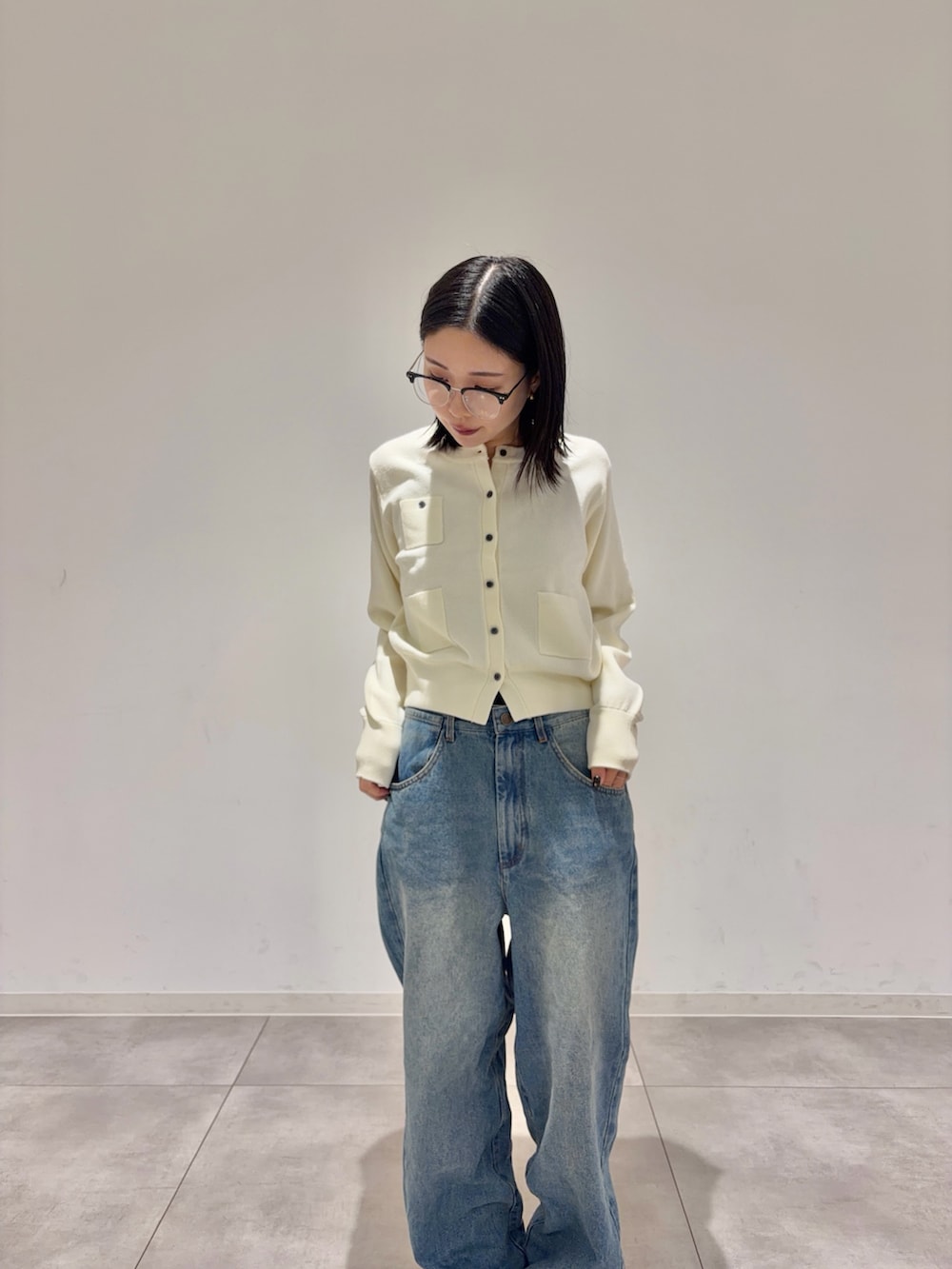 ホワイト系のカーディガン/ボレロ、ブルー系のデニムパンツ、ブラック系のブーツを着用したレディースの秋コーディネートの2枚目の写真