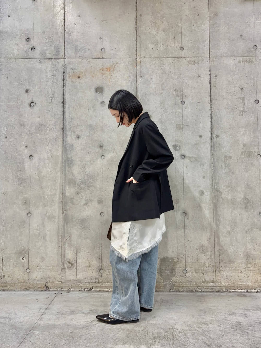 ブラック系のテーラードジャケット、ホワイト系のキャミソール、ブルー系のデニムパンツを着用したレディースの春コーディネートの3枚目の写真