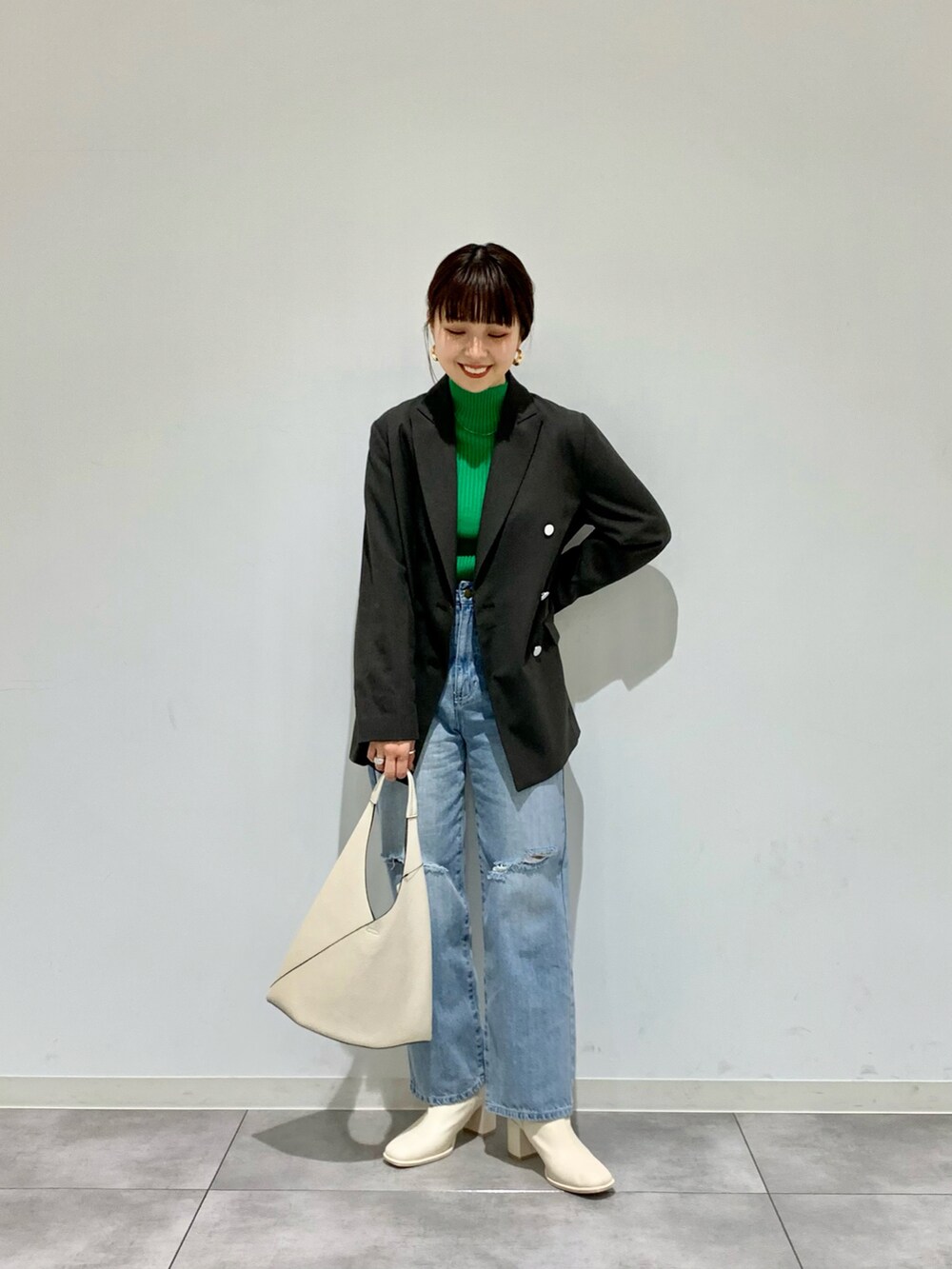 ブルー系のデニムパンツ、グレー系のテーラードジャケット、グリーン系のニット/セーターを着用したレディースの春コーディネートの2枚目の写真