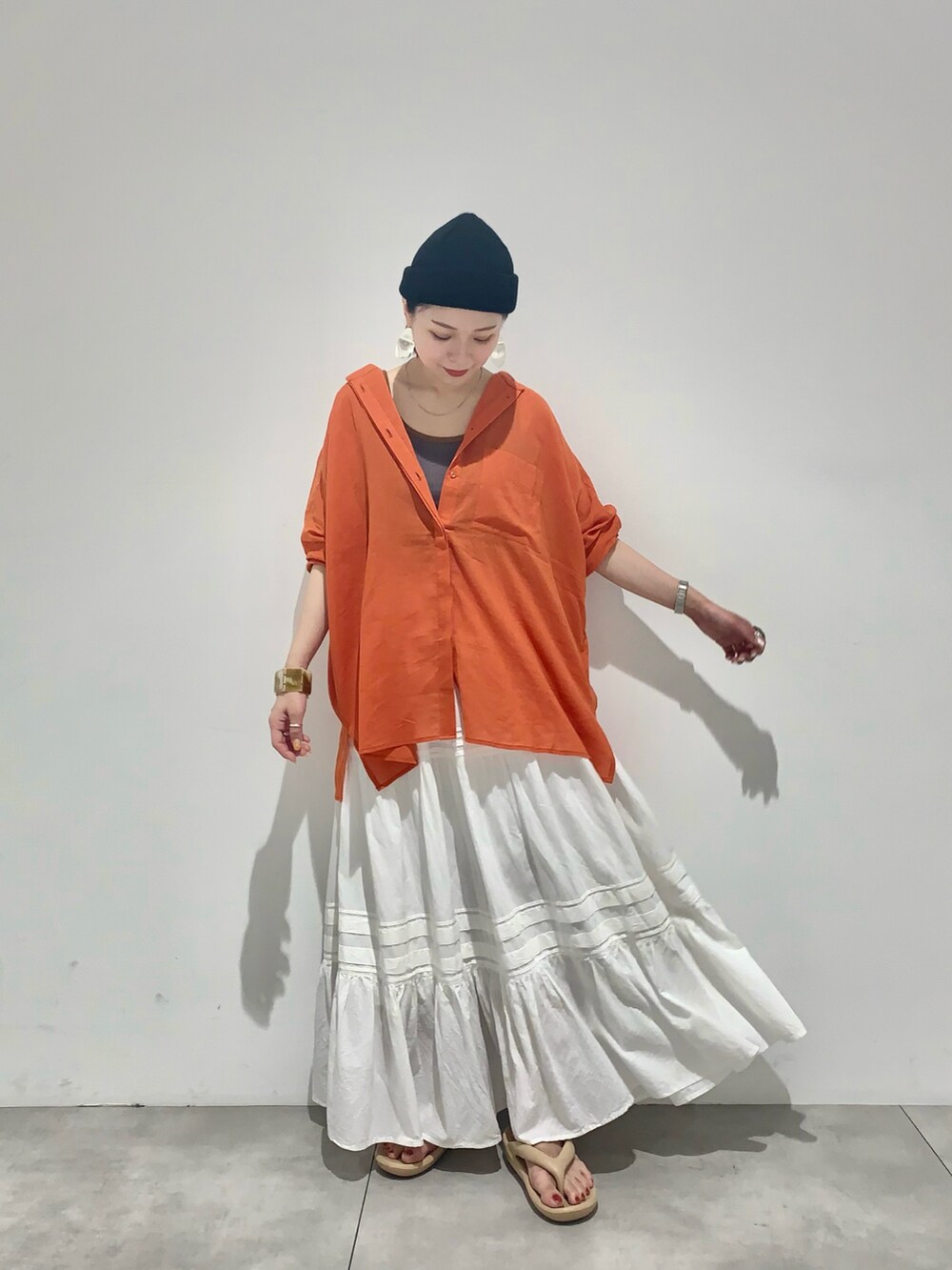 オレンジ系のシャツ/ブラウス、ピンク系のタンクトップ、ホワイト系のスカートを着用したレディースの夏コーディネートの2枚目の写真