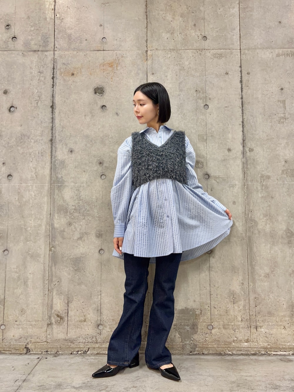 グレー系のベスト、ブルー系のワンピース、ブルー系のデニムパンツを着用したレディースの冬コーディネートの3枚目の写真